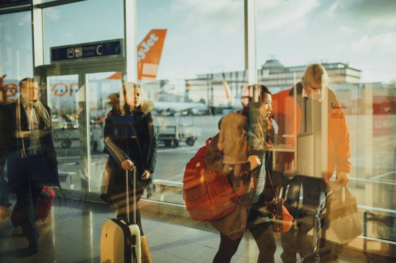 voyageurs à l'aéroport derrière une cloison vitrée